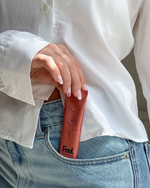 A close-up, high-fashion style shot featuring a Pro Collagen supplement sachet held in a white shirt pocket against denim.